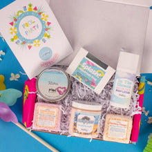 Load image into Gallery viewer, Assorted beauty products including a book, soap, and lotion in a box on a blue background.