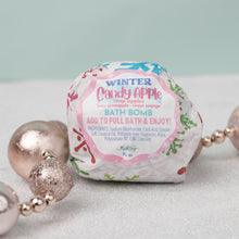 Load image into Gallery viewer, A packaged bath bomb with &#39;Winter Candy Apple&#39; label, surrounded by decorative pearls on a light background.