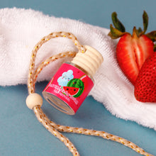 Load image into Gallery viewer, Small bottle with a colorful label on a rope, next to strawberries on a white towel.