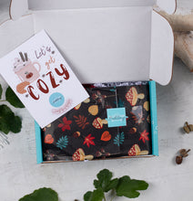 Load image into Gallery viewer, Open box with a patterned fabric and a card inside, on a light wooden surface with leaves.