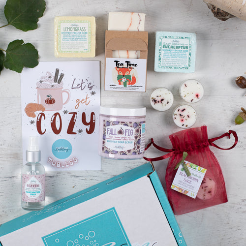 Collection of self-care products including candles, soap, and SHOWER STEAMERS on a wooden surface.