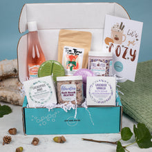 Load image into Gallery viewer, Gift box with self-care products including a bottle, tea, and bath salts on a white surface.